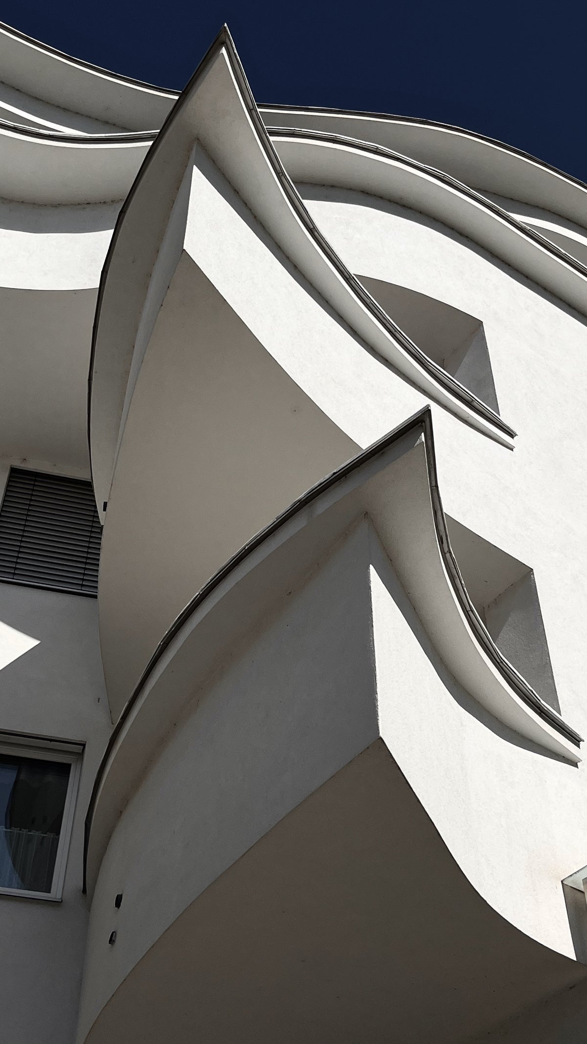 Modern architectural structure with curved white walls against a blue sky