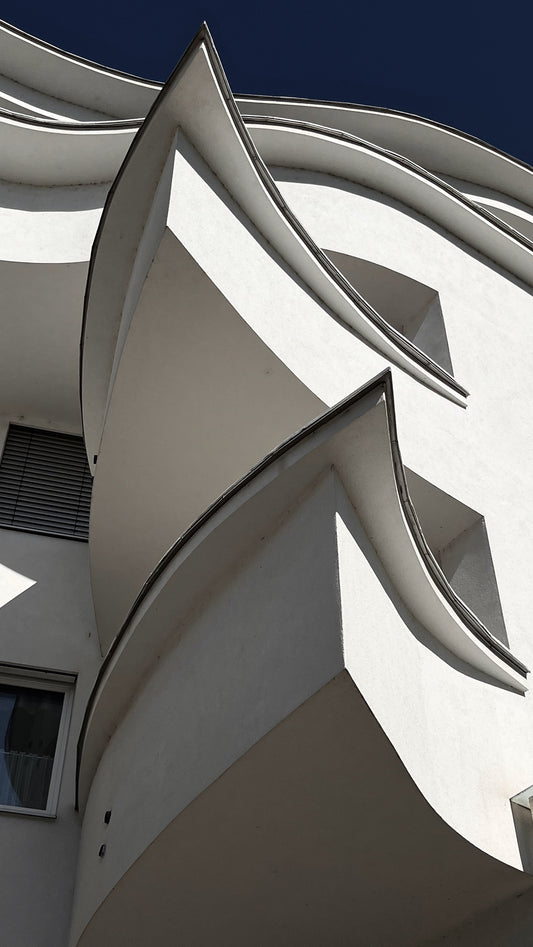 Modern architectural structure with curved white walls against a blue sky